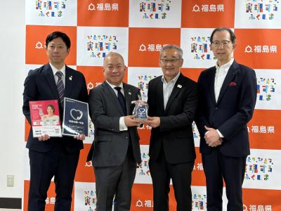 電話お願い手帳を持って微笑むNTT東日本福島支店川辺企画総務部長、大橋支店長、吉田会長、内堀知事